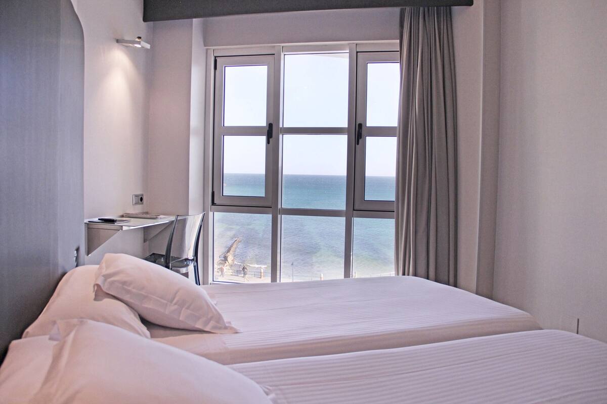Una habitación de hotel con un ventanal grande, una cama y un escritorio con silla.
