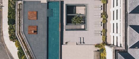 An aerial view of a rooftop with a swimming pool, seating areas, and a garden.