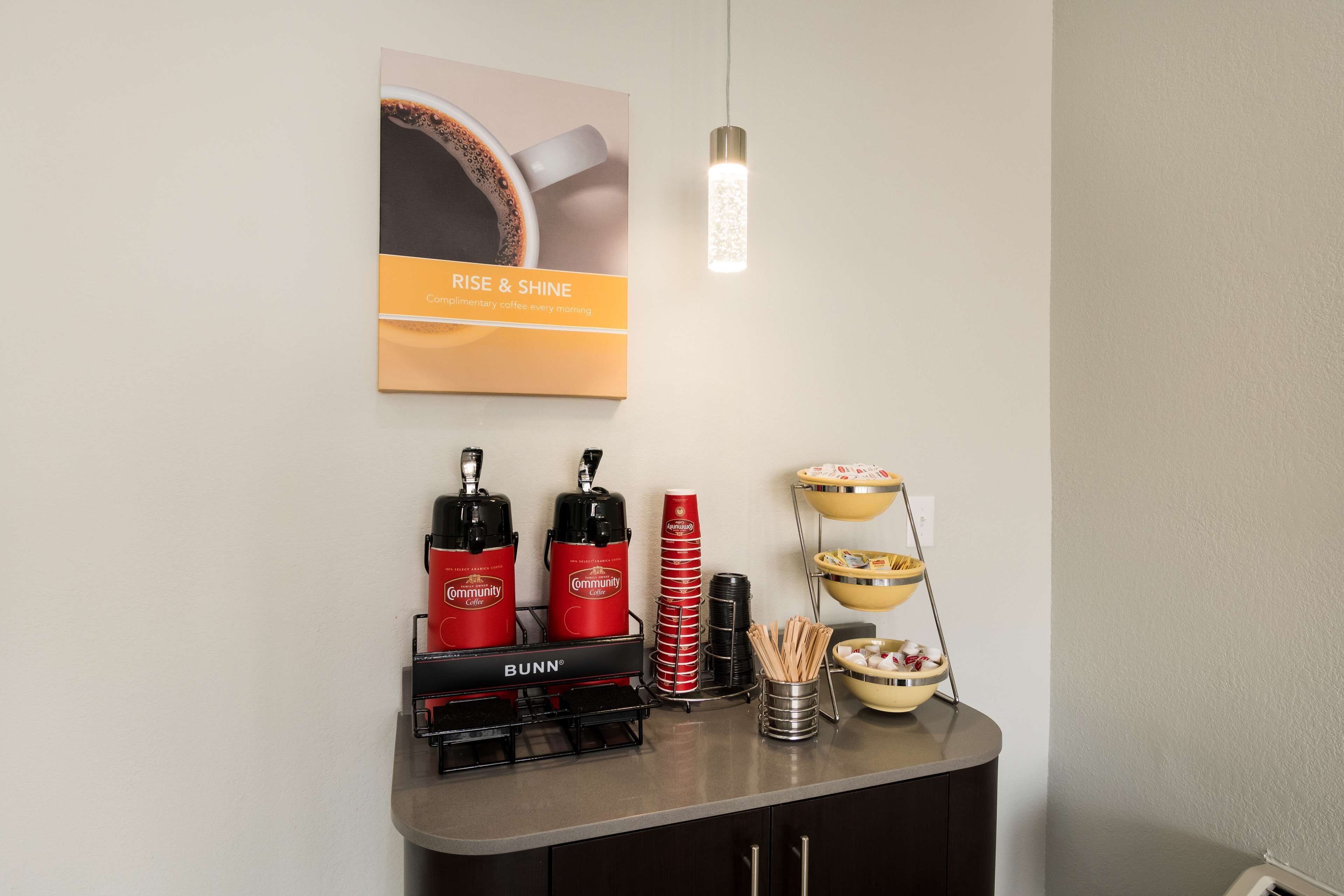 Un coin café équipé de machines à café Bunn, de tasses rouges et d’une pancarte sur laquelle on peut lire : « LEVEZ-VOUS ET PASSEZ À L’ACTION ».