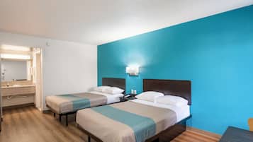 A hotel room with two beds, a bathroom, and a desk.