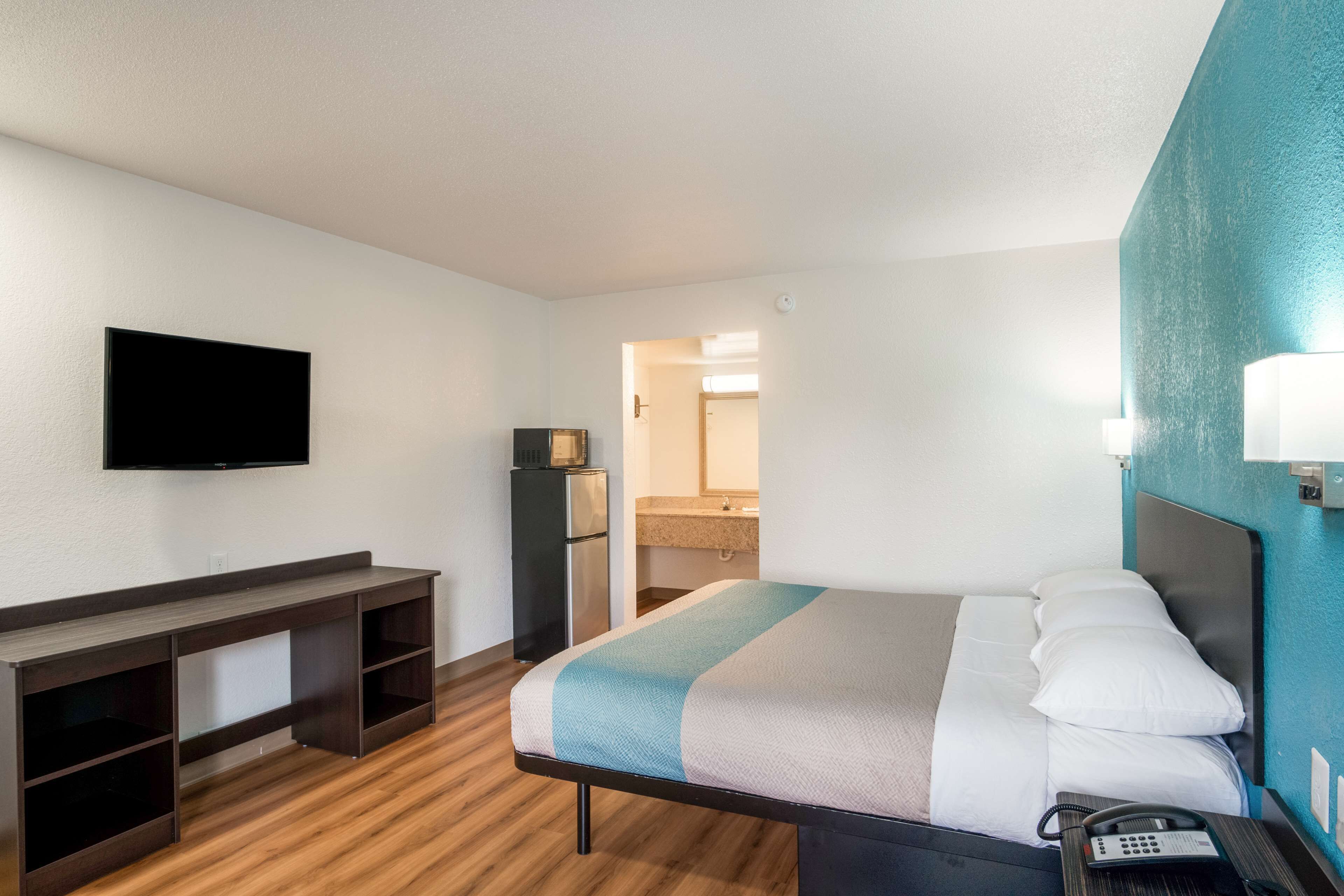 A hotel room with a bed, a desk, a television, and a phone.