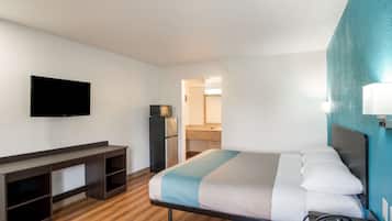 A hotel room with a bed, a desk, a television, and a phone.