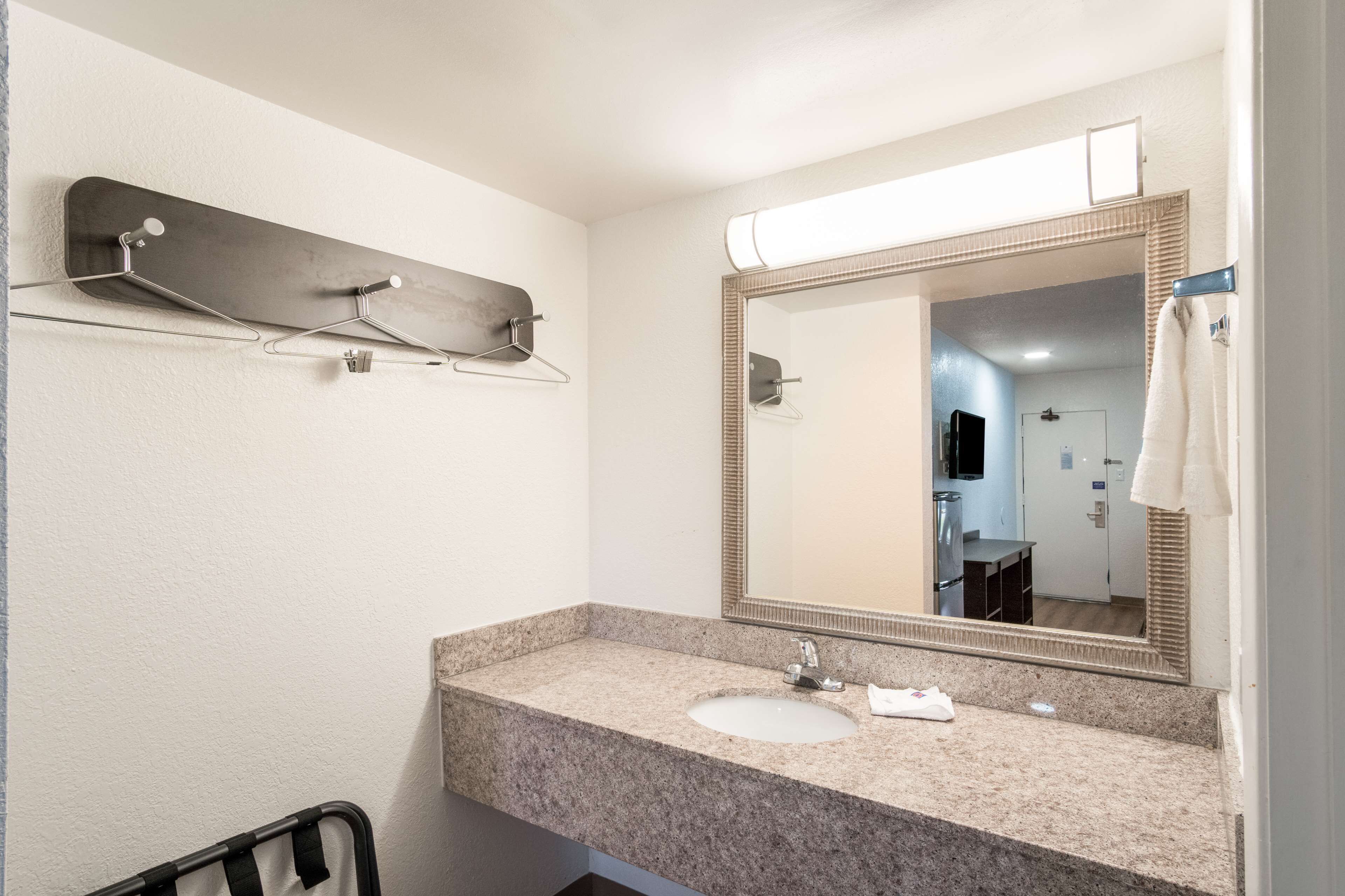 A bathroom with a granite countertop, a sink, a mirror, and a towel rack.