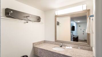 A bathroom with a granite countertop, a sink, a mirror, and a towel rack.