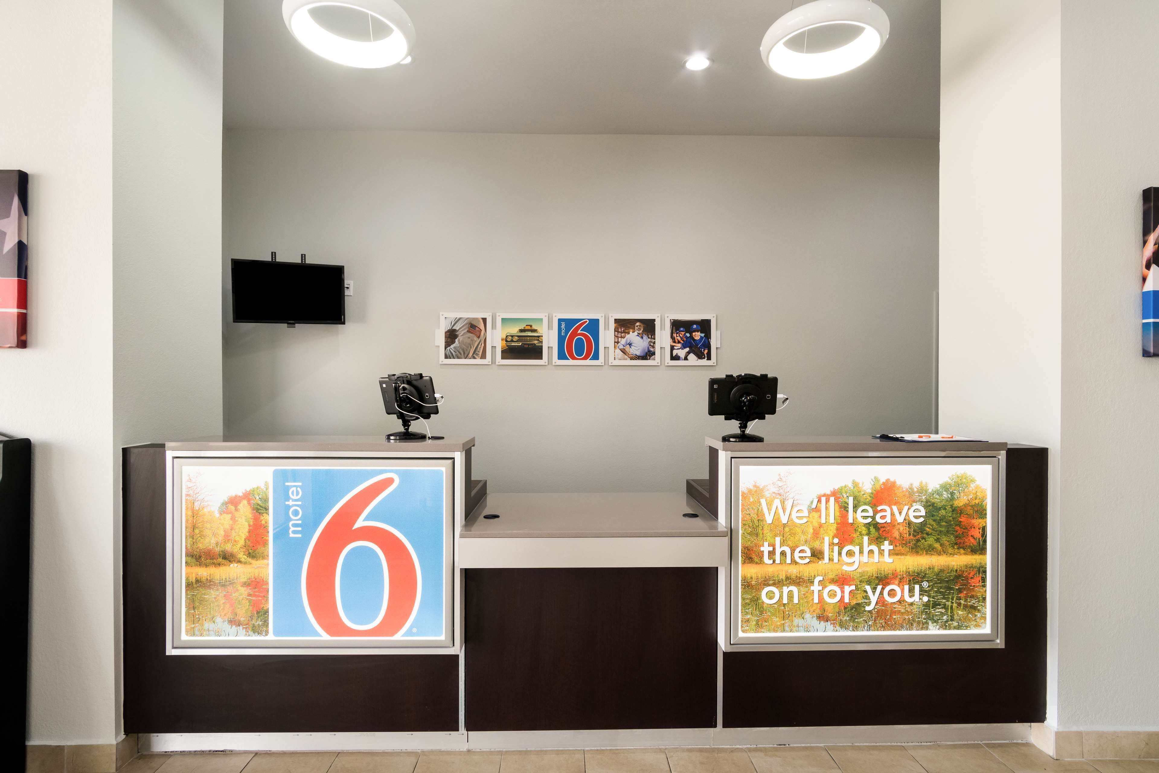A hotel reception desk with a large sign reading "6" and a message stating "We'll leave the light on for you."