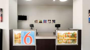 A hotel reception desk with a large sign reading "6" and a message stating "We'll leave the light on for you."