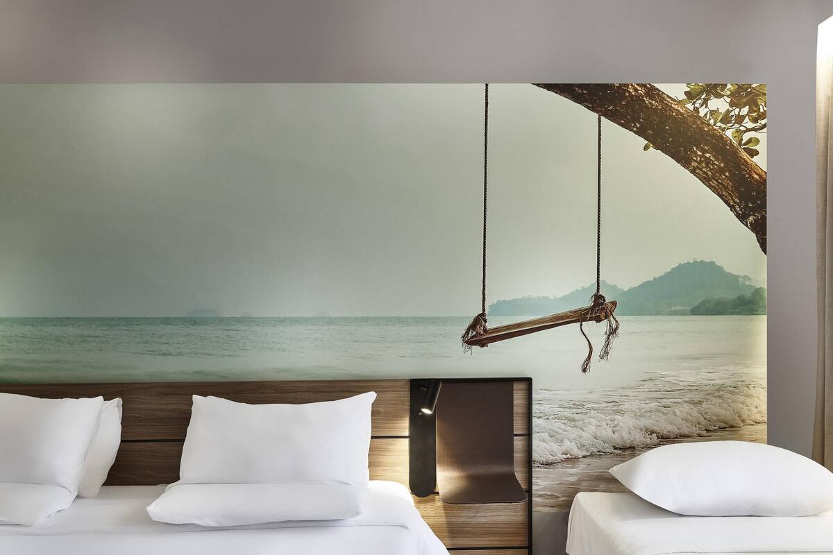 Een slaapkamer met een bed, een houten hoofdbord en een groot wanddecor met een strandthema.