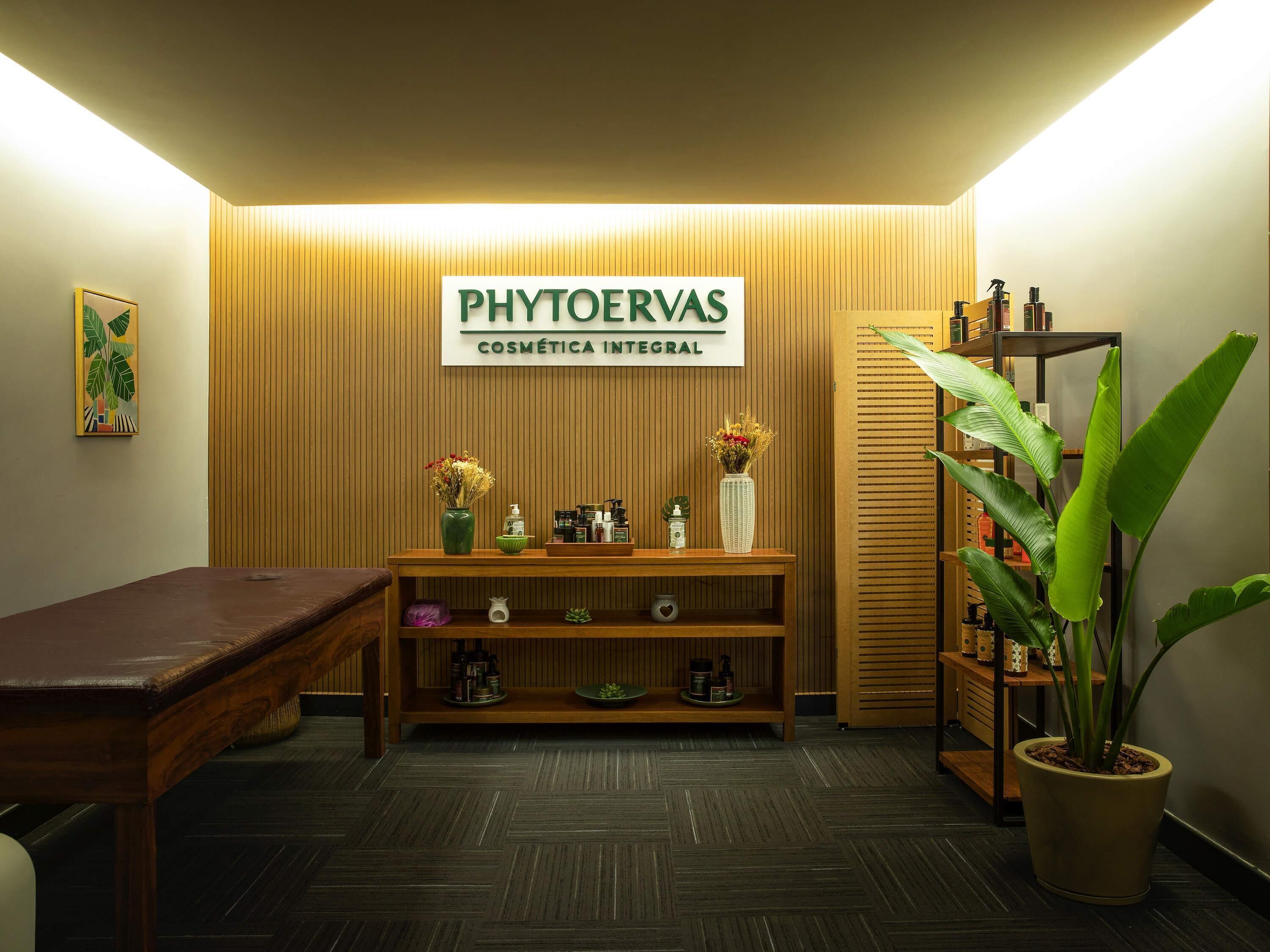 A reception area with a reception desk, a sign reading 'PHYTOERVAS COSMETICA INTEGRAL', a potted plant, and a shelf with various items.