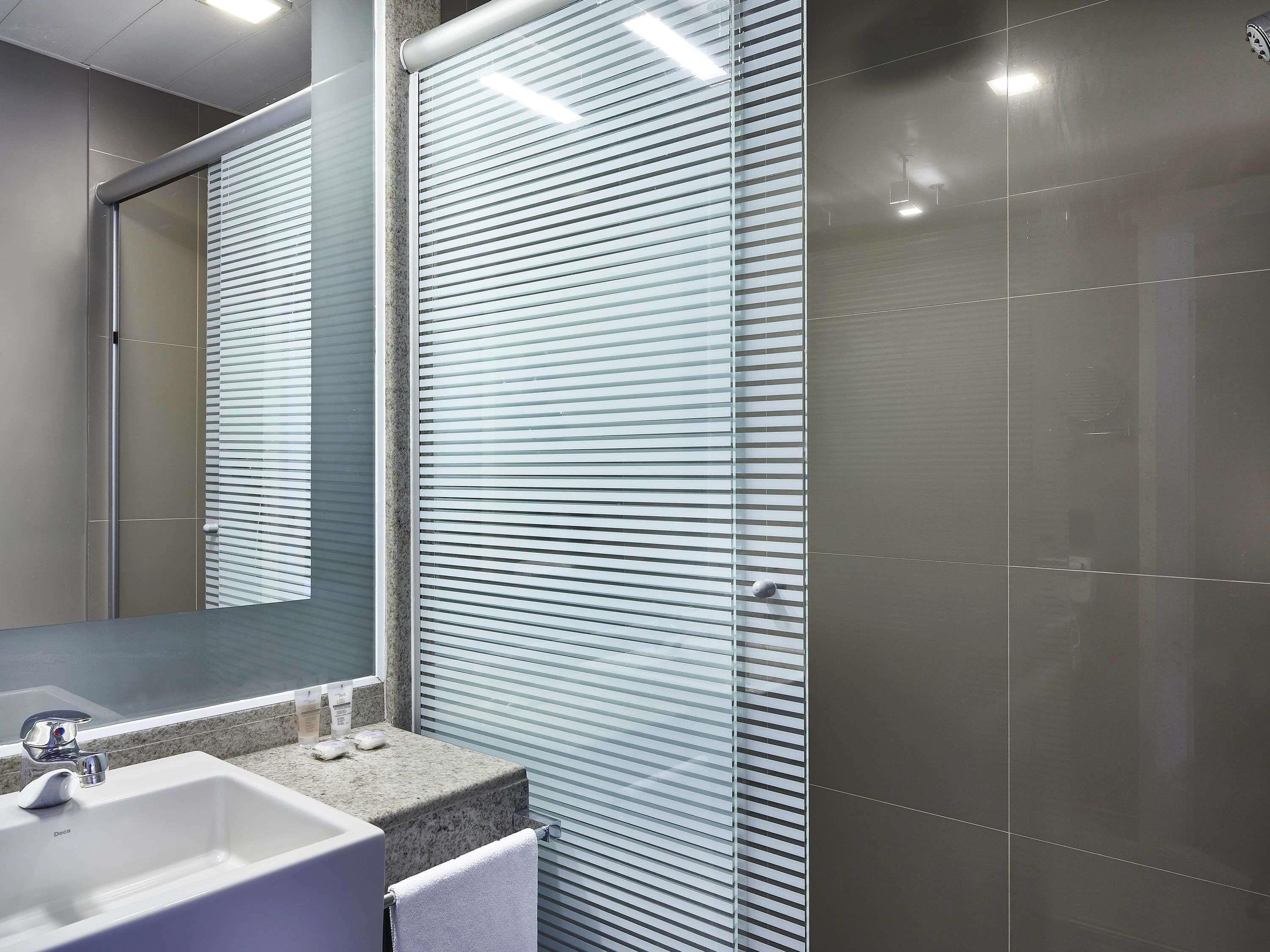 Een moderne badkamer met een grote spiegel, een wastafel en een douchecabine van glas.