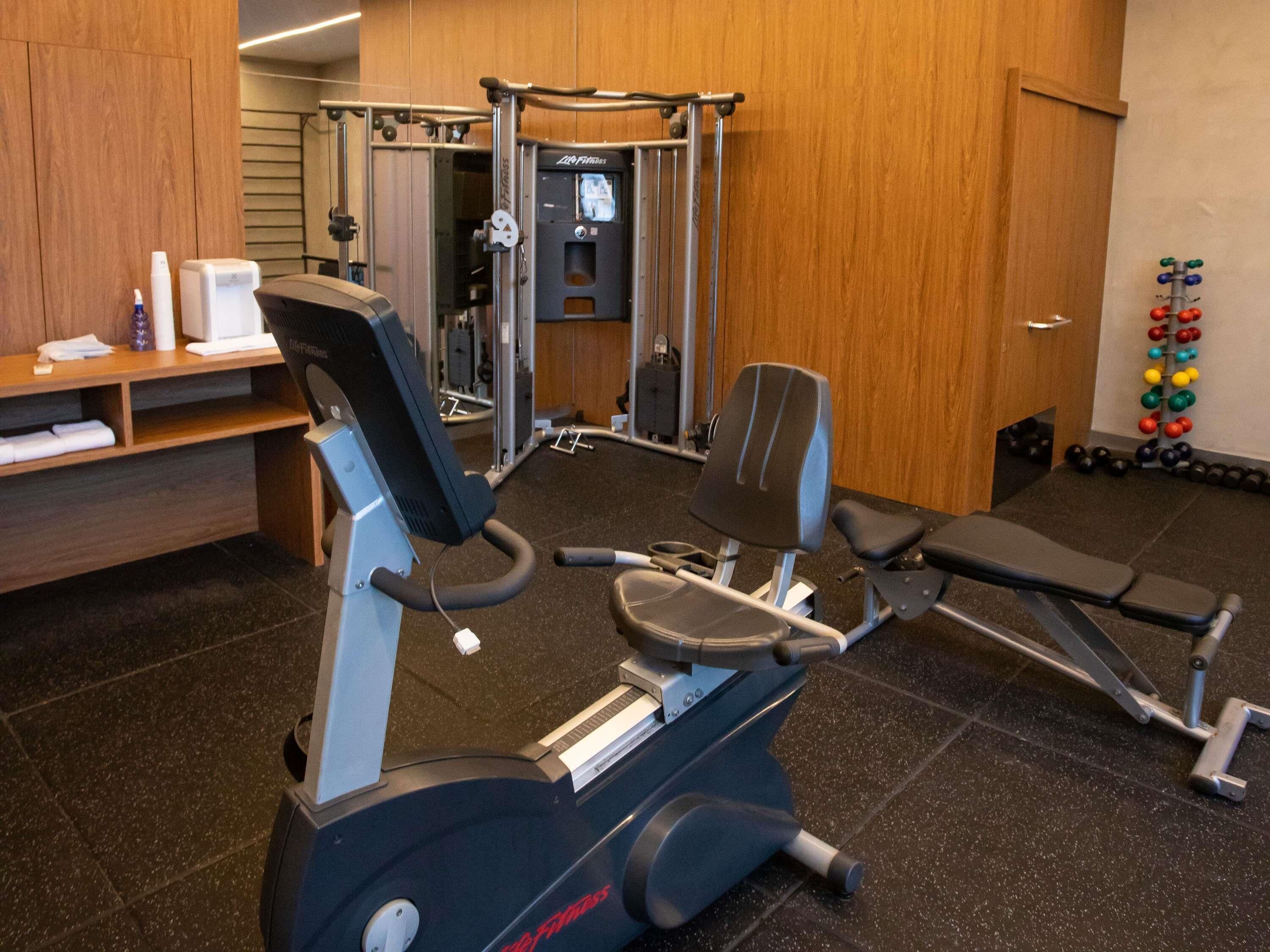 Una palestra con attrezzature cardio, macchine per pesi e una rastrella per squat.