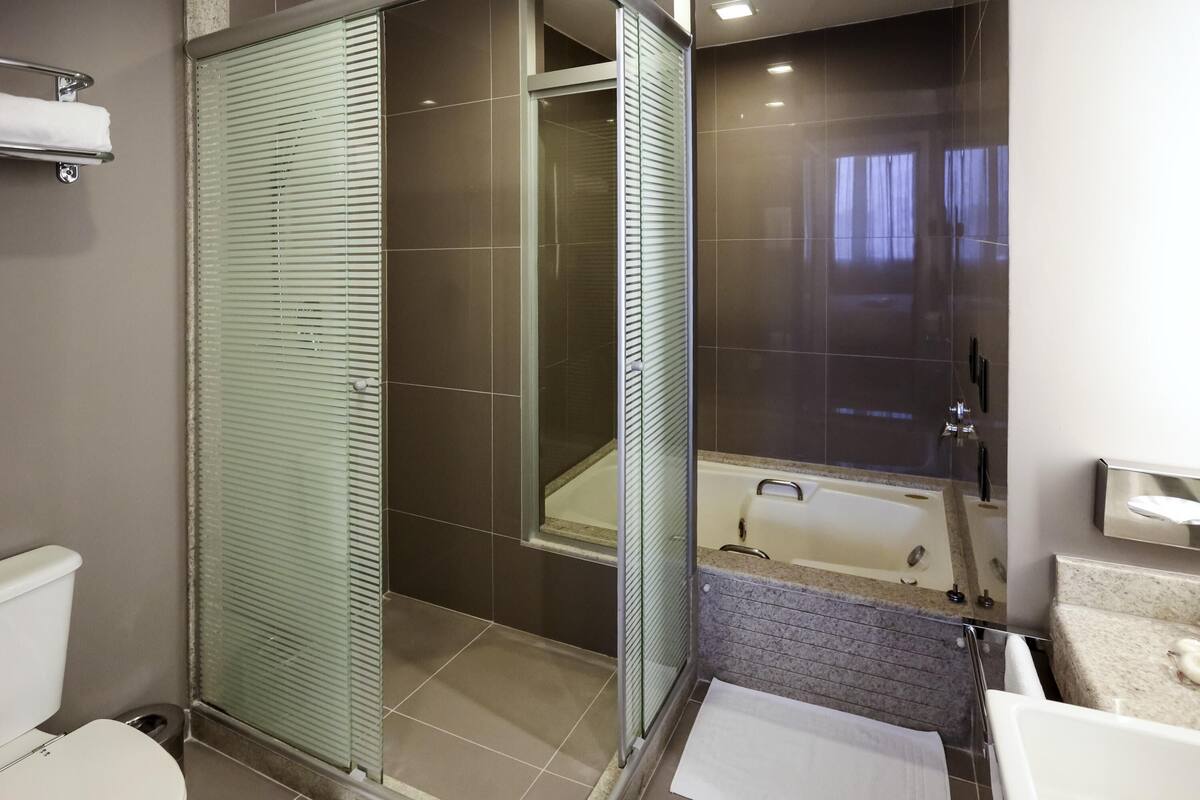 A modern bathroom with a glass-enclosed shower, a bathtub, and a toilet.