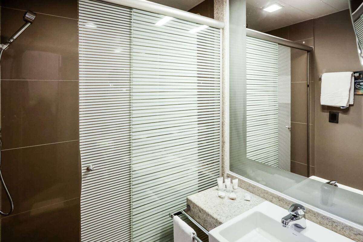 A modern bathroom with a shower, a sink, and a large mirror.