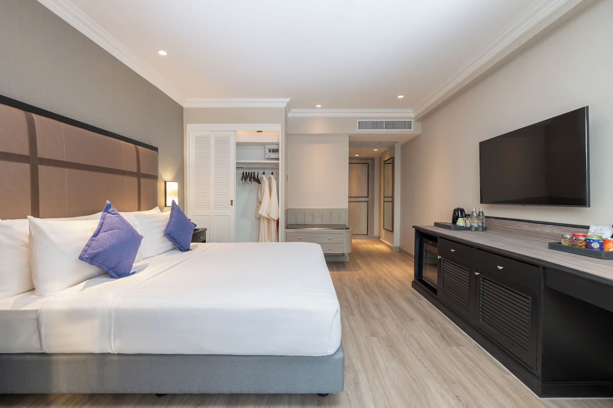 Une chambre d’hôtel moderne dotée d’un grand lit, d’une télévision à écran plat, d’un minibar et d’un dressing.