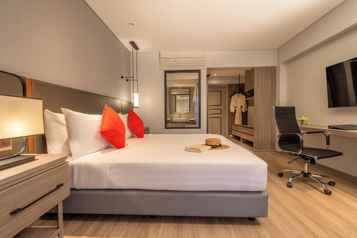 Une chambre d’hôtel comprenant un lit, une table de chevet, une lampe et un bureau avec une chaise.