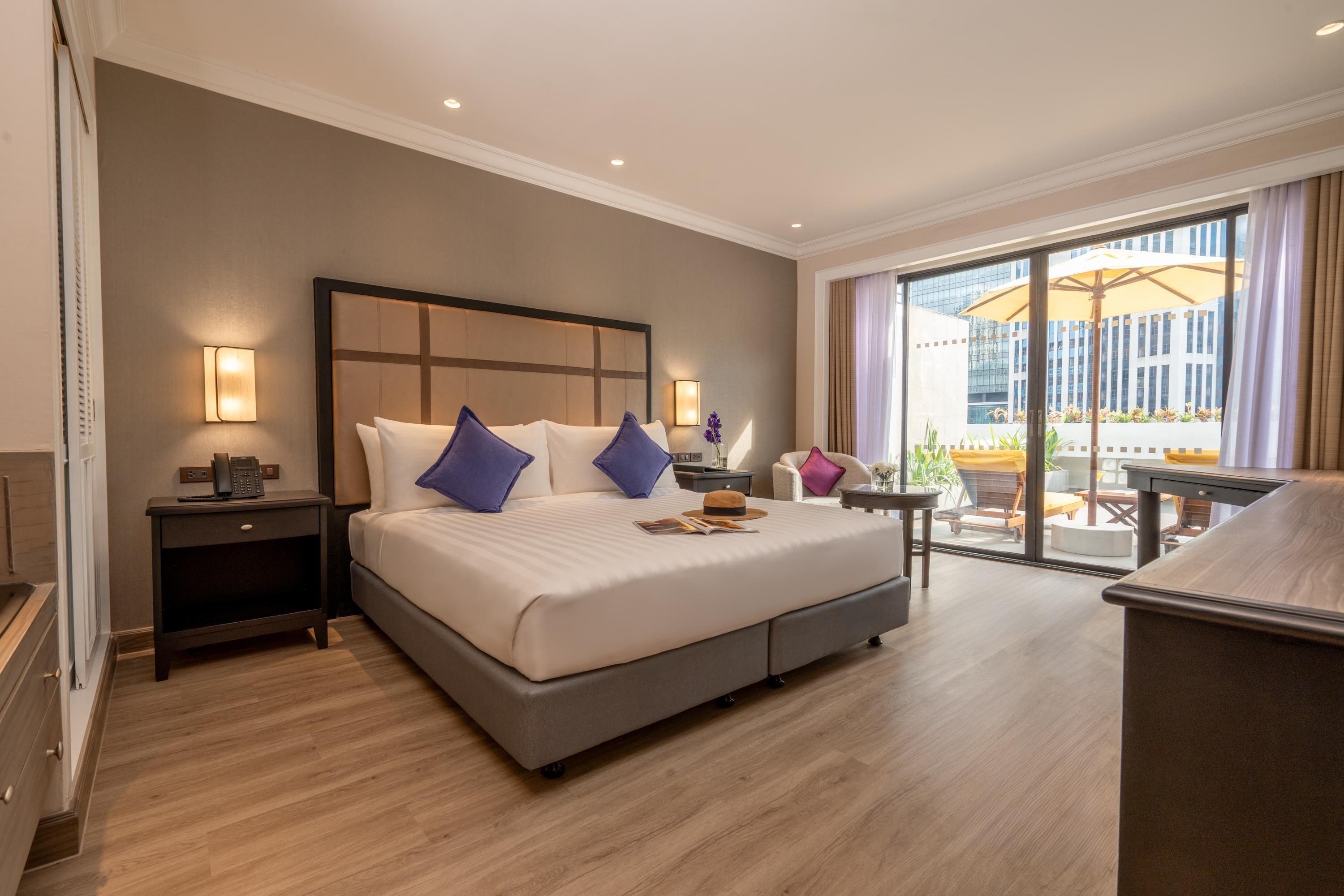 A hotel room with a large bed, a desk, and a view of the city through the window.
