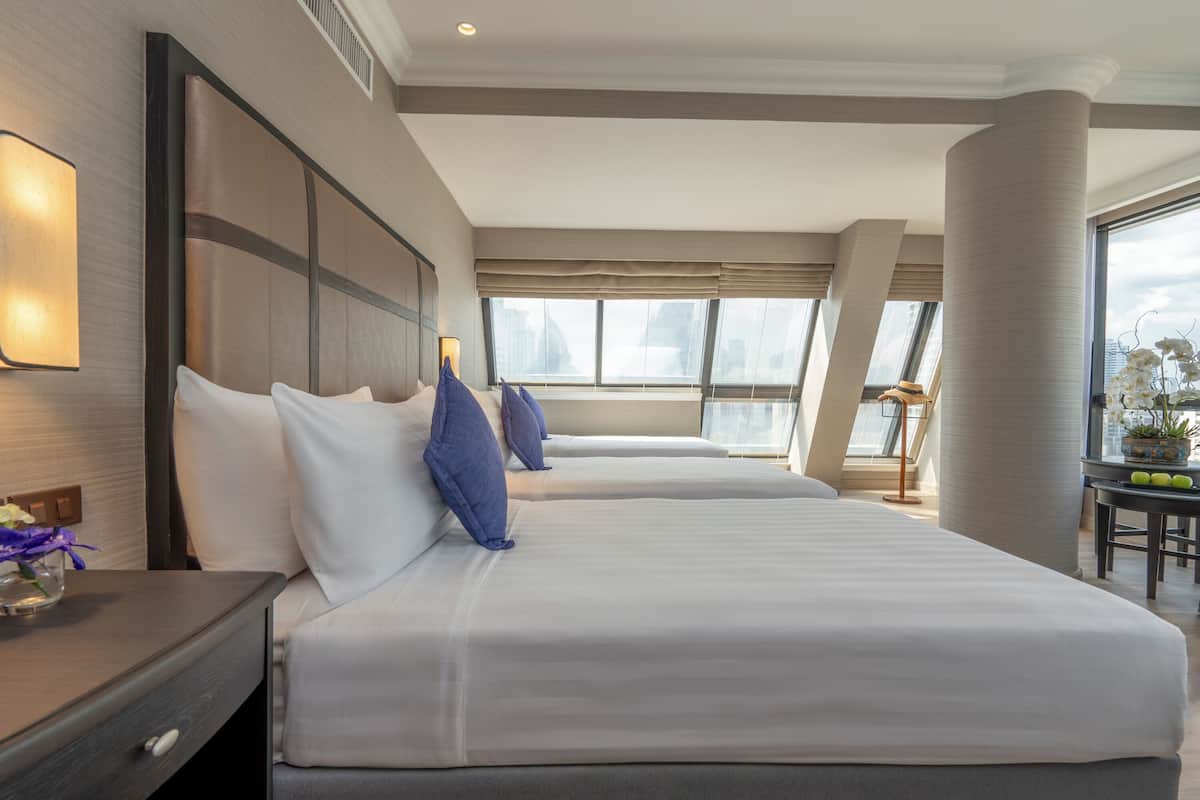 Une chambre d’hôtel avec deux lits, une table de chevet, une lampe et une vue sur la ville.