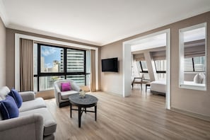 Un salon moderne comprenant un canapé, un fauteuil, une table basse et un téléviseur fixé au mur.