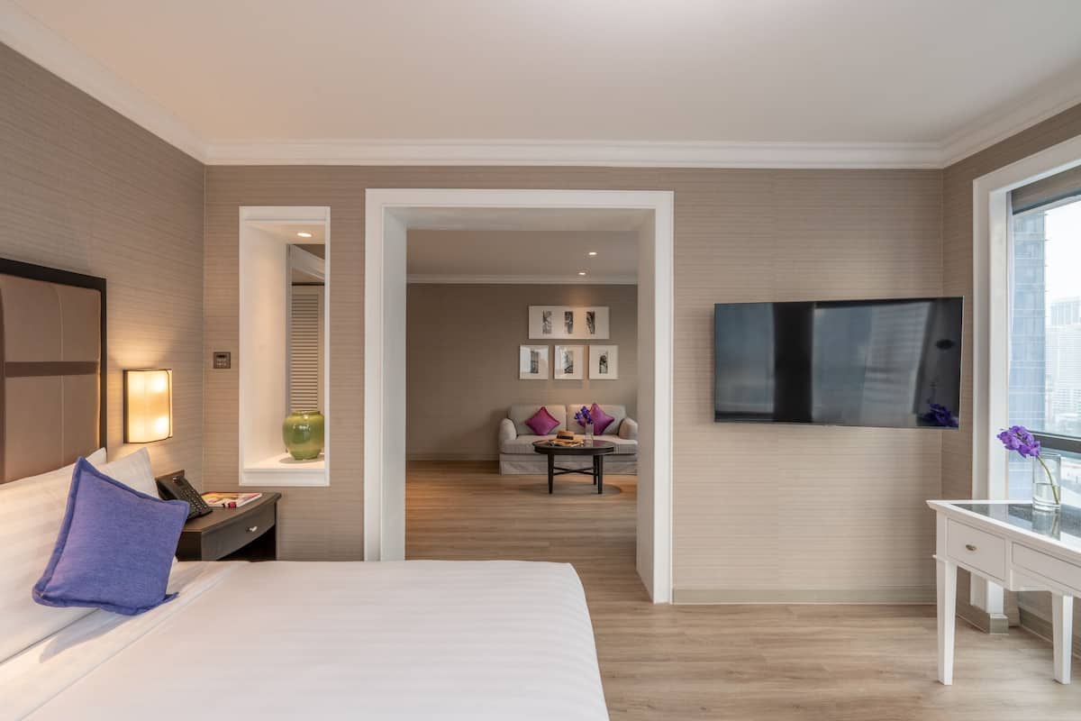 Une chambre d’hôtel équipée d’un lit, d’une table de chevet, d’une lampe, d’une télévision et donnant sur le couloir.