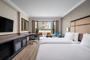 Ein Hotelzimmer mit Bett, Schreibtisch, Stuhl, Fernseher und Blick auf die Stadt.