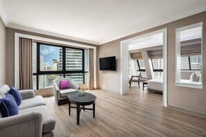 Ein modernes Wohnzimmer mit Sofa, Sessel, Couchtisch und einem an der Wand befestigten Fernseher.