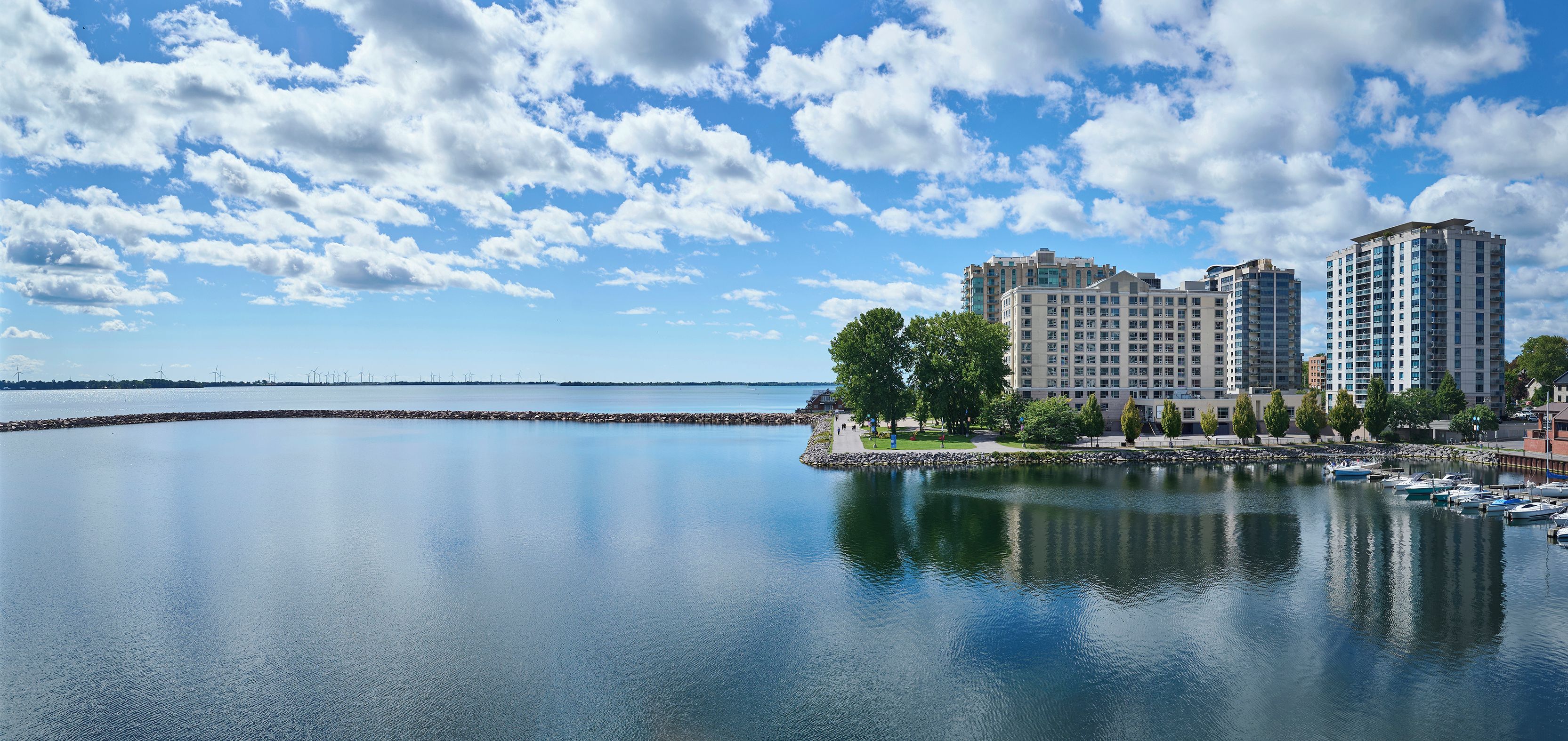 A waterfront property with multiple high-rise buildings, a calm body of water, and a clear sky.