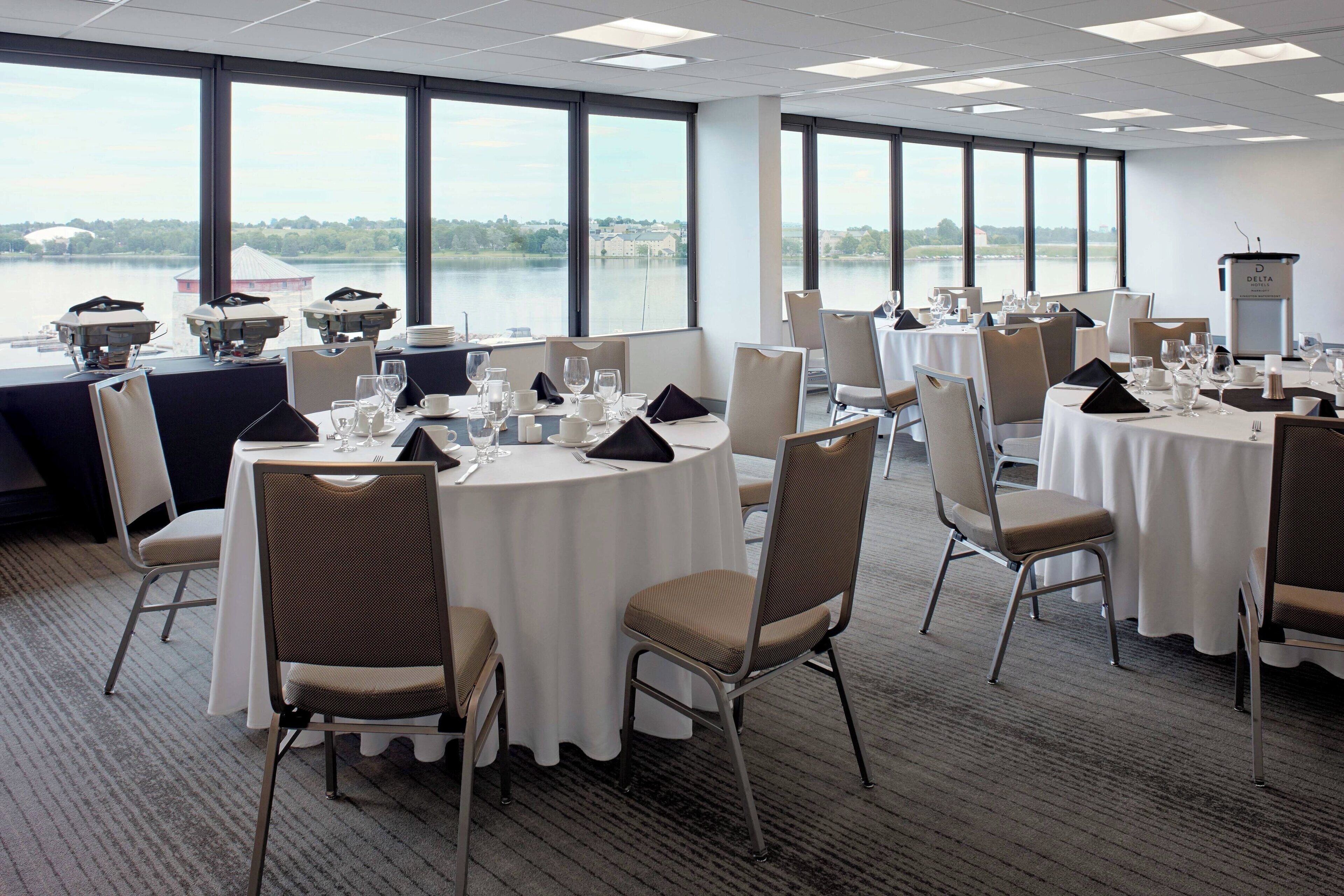 A conference room with round tables, chairs, and a view of a lake.