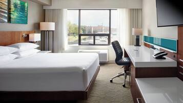 A hotel room with a large bed, a desk with a computer, a chair, and a TV.