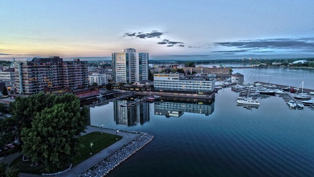 Puerto deportivo con barcos amarrados, rodeado de edificios modernos y una superficie acuática tranquila que refleja las construcciones.