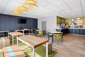 A modern interior with tables and chairs, a flat-screen TV, and a kitchen area. - Spark by Hilton Staunton (Staunton)
