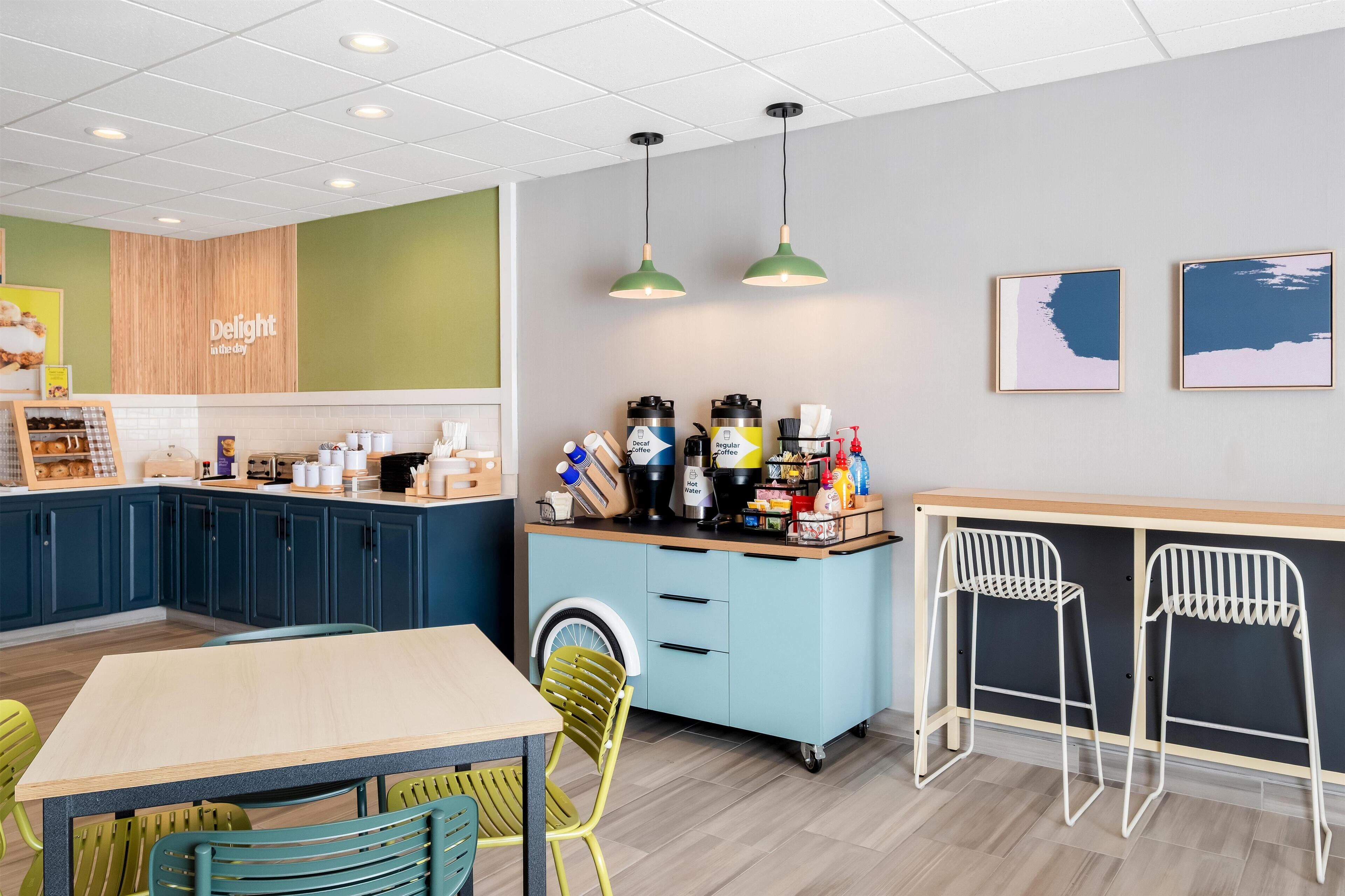 A modern kitchen area with a dining table, chairs, a coffee station, and a washing machine.