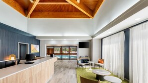 A hotel lobby with a reception desk, seating area, and a pool view.