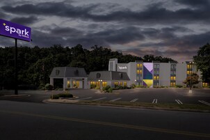 Un hotel de diseño moderno, con un llamativo letrero 'spark by Hilton', varias construcciones y un estacionamiento.
