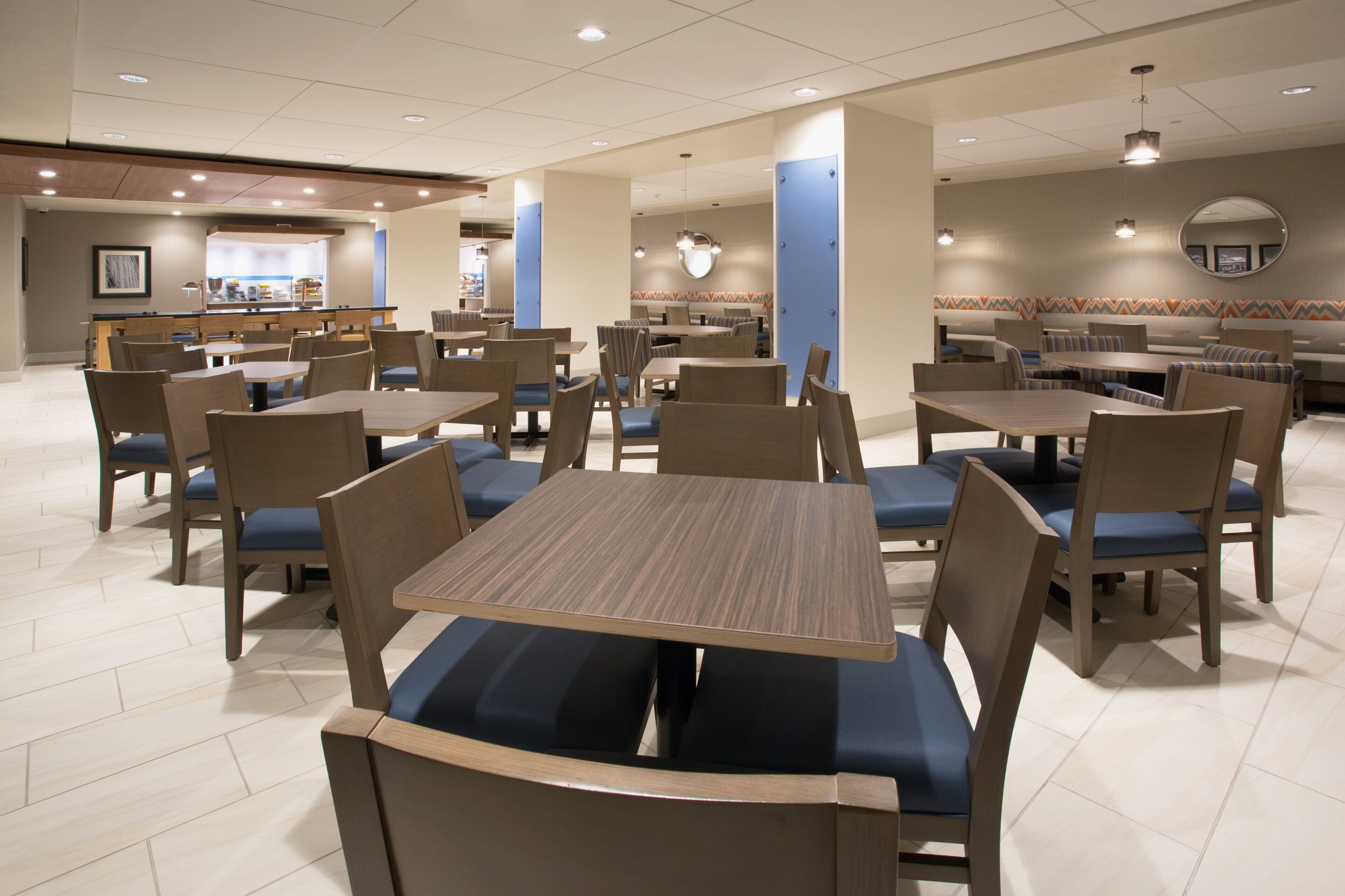 A spacious dining area with multiple tables and chairs, a counter with a menu, and a patterned wall.