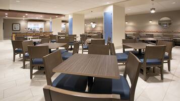 A spacious dining area with multiple tables and chairs, a counter with a menu, and a patterned wall.