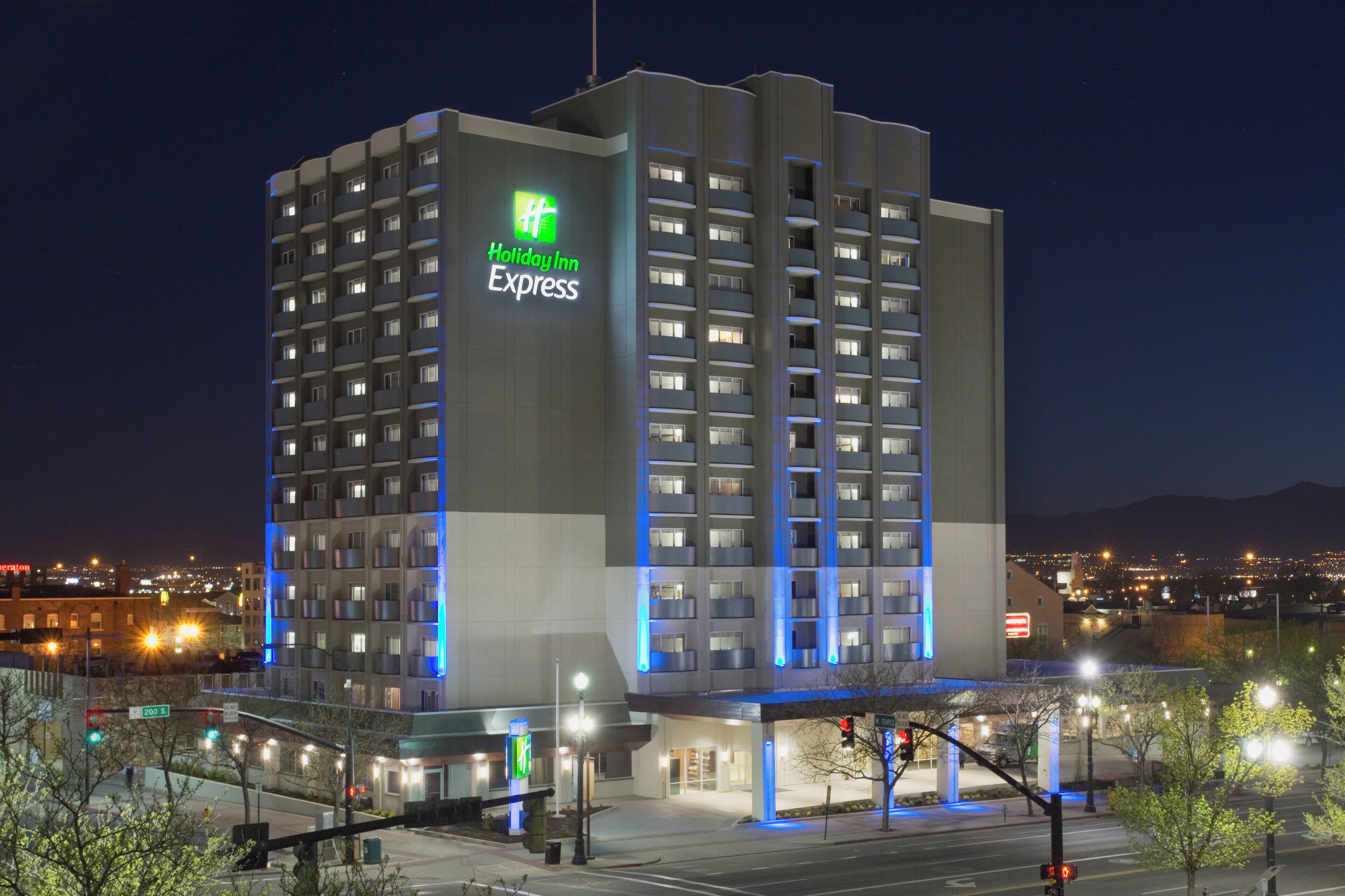 Um hotel Holiday Inn Express com vários andares, um letreiro verde chamativo, diversas varandas e uma fachada moderna.