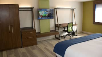 Habitación de hotel con cama, escritorio con silla, armario y televisor de pared mostrando un pronóstico del tiempo.