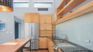 A modern kitchen with wooden cabinets, stainless steel appliances, and a black countertop. - Tilden Hotel (San Francisco)