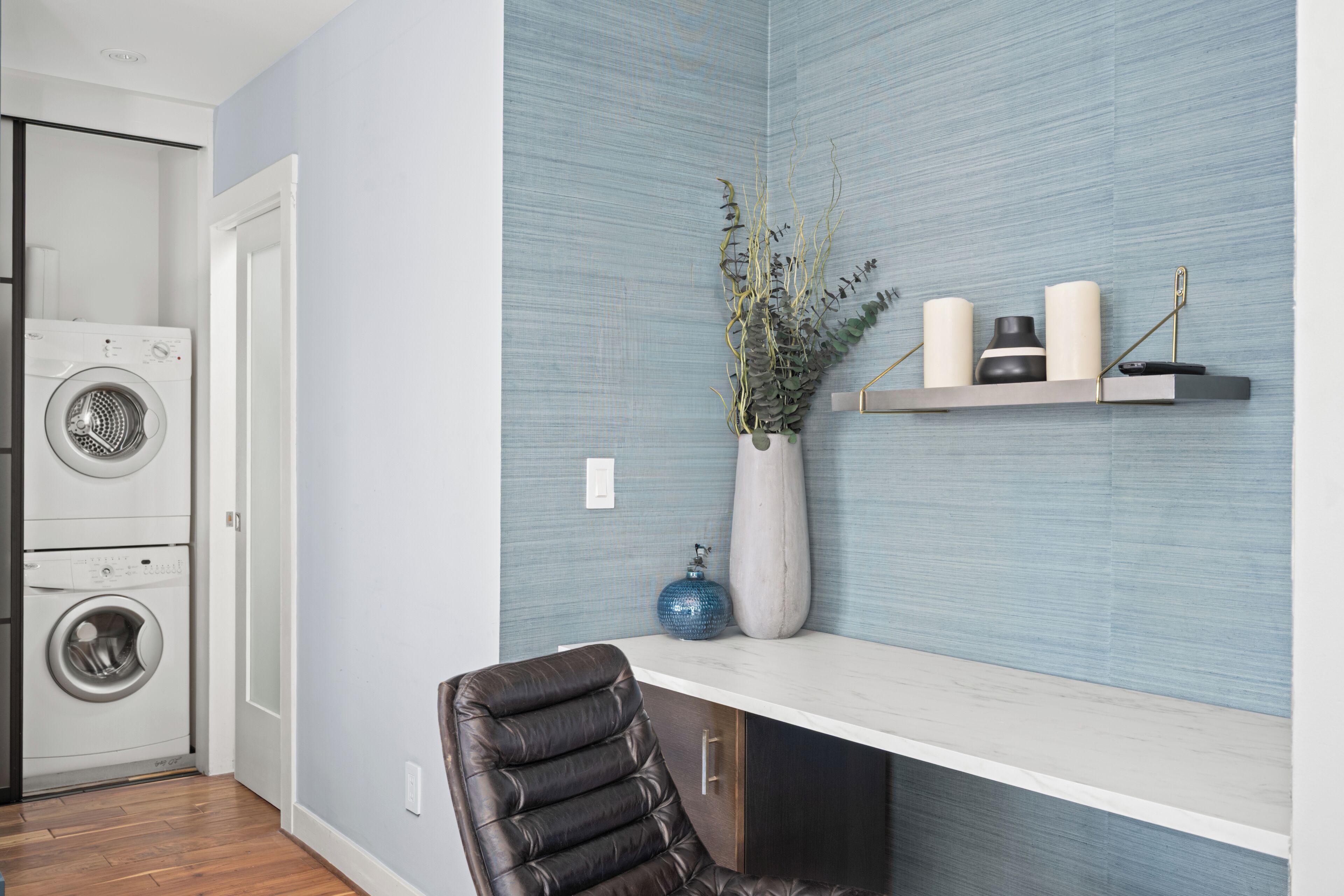 A laundry room with a washing machine, a dryer, and a shelf with decorative items.