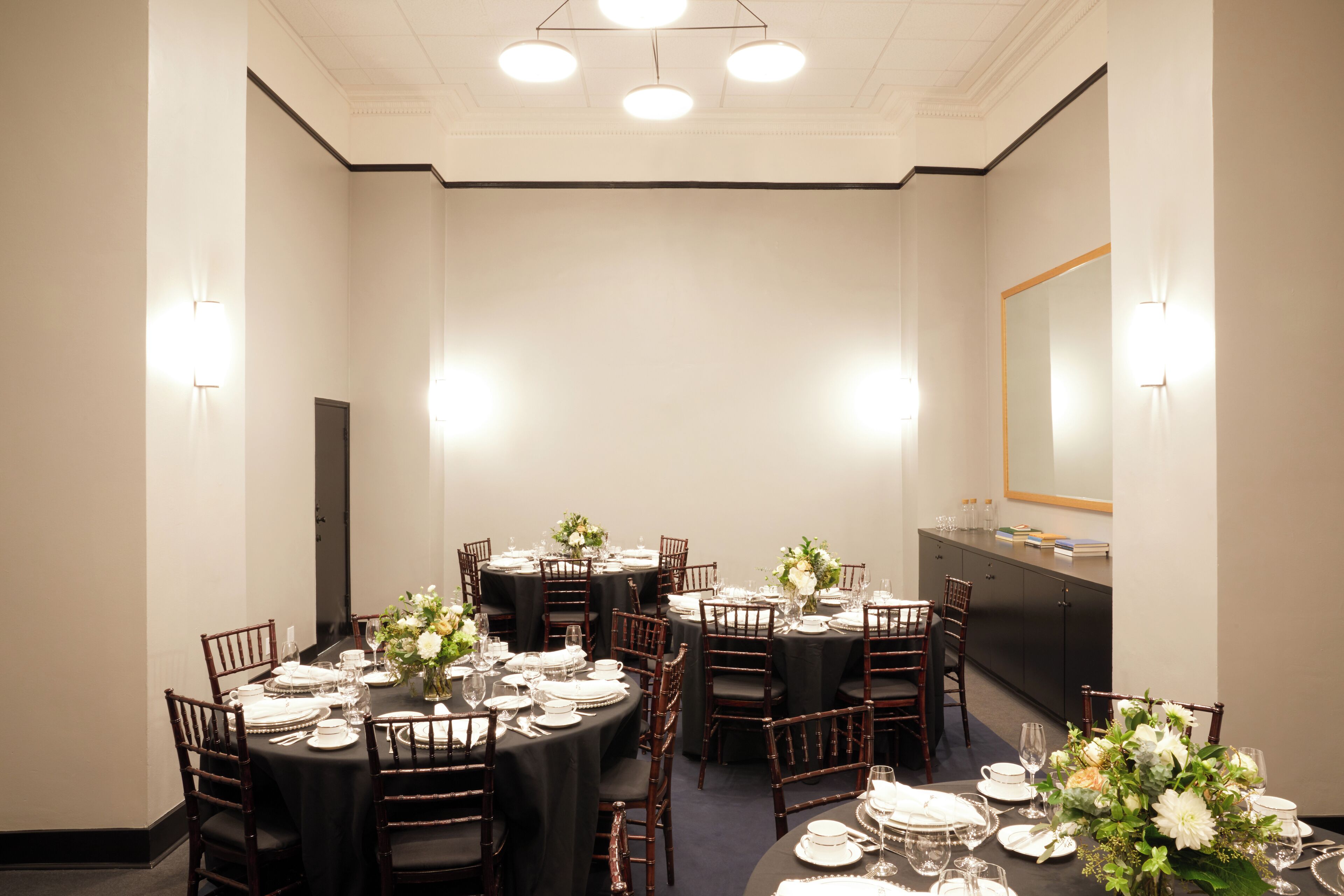 A conference room with round tables, chairs, and a buffet counter.