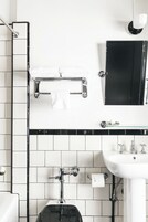 A modern bathroom with a white and black tiled backsplash, a white sink with chrome fixtures, and a black cabinet above the mirror.