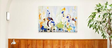 A room with a blue sofa, a wooden headboard, a painting on the wall, and a potted plant.