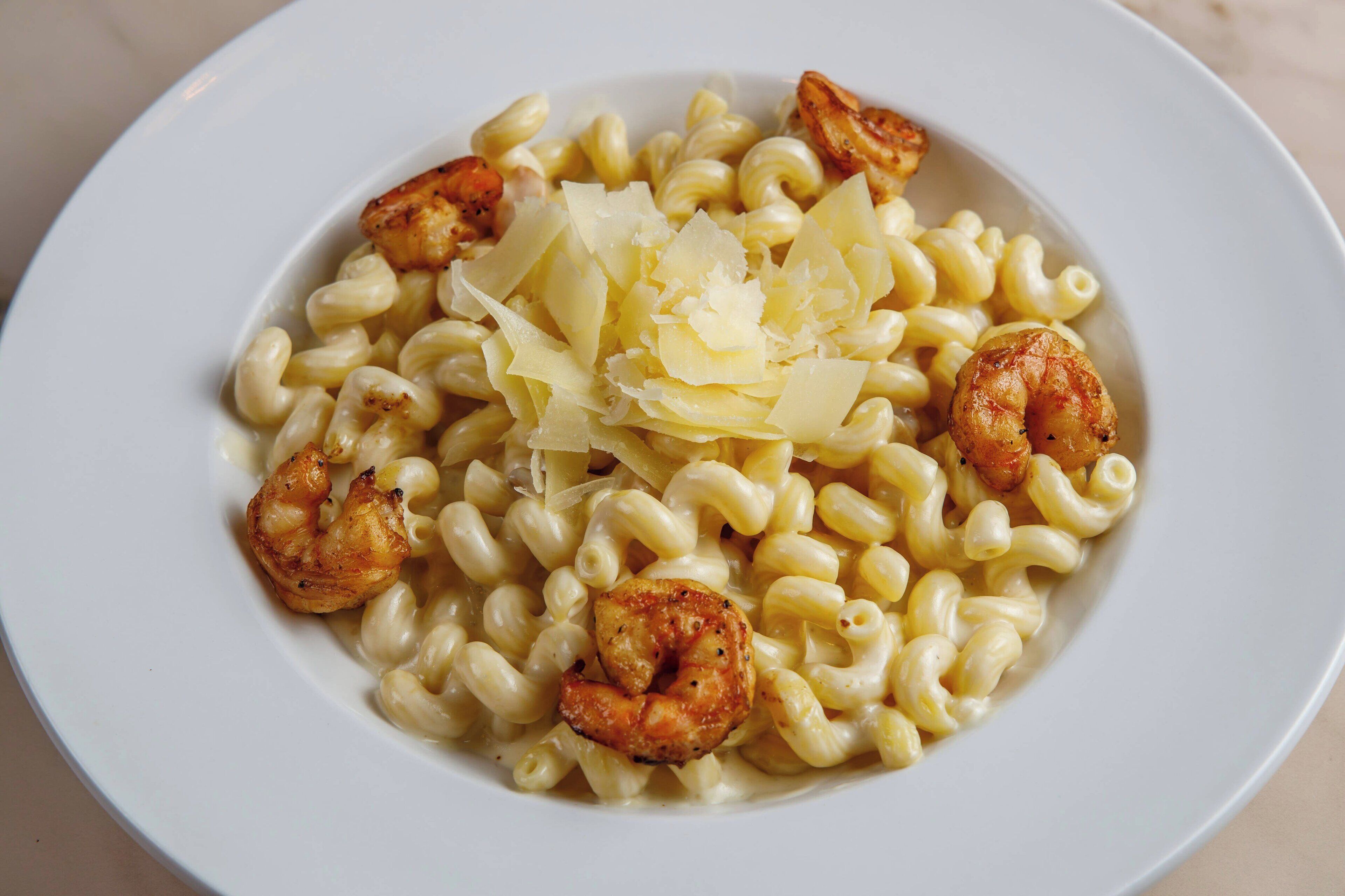 Une assiette de pâtes aux crevettes, saupoudrée de fromage râpé.