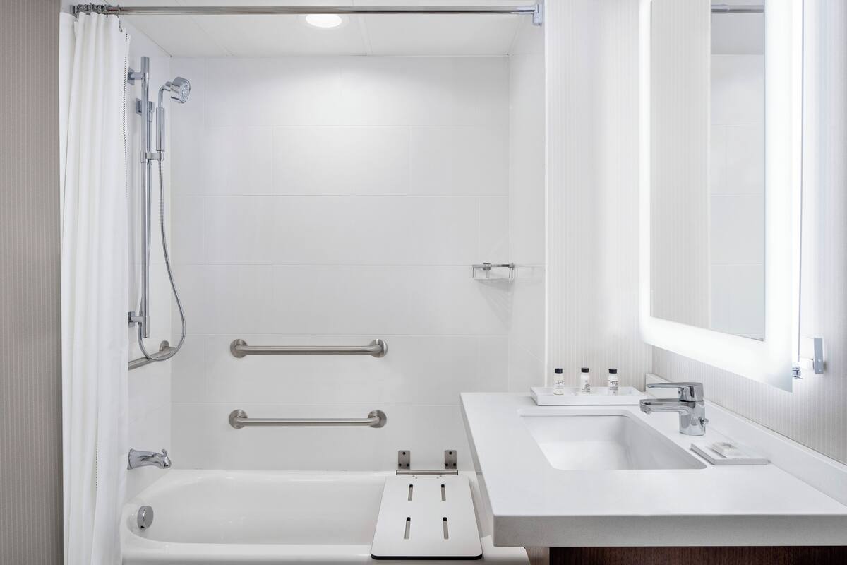 A modern bathroom with a bathtub, shower, and sink.