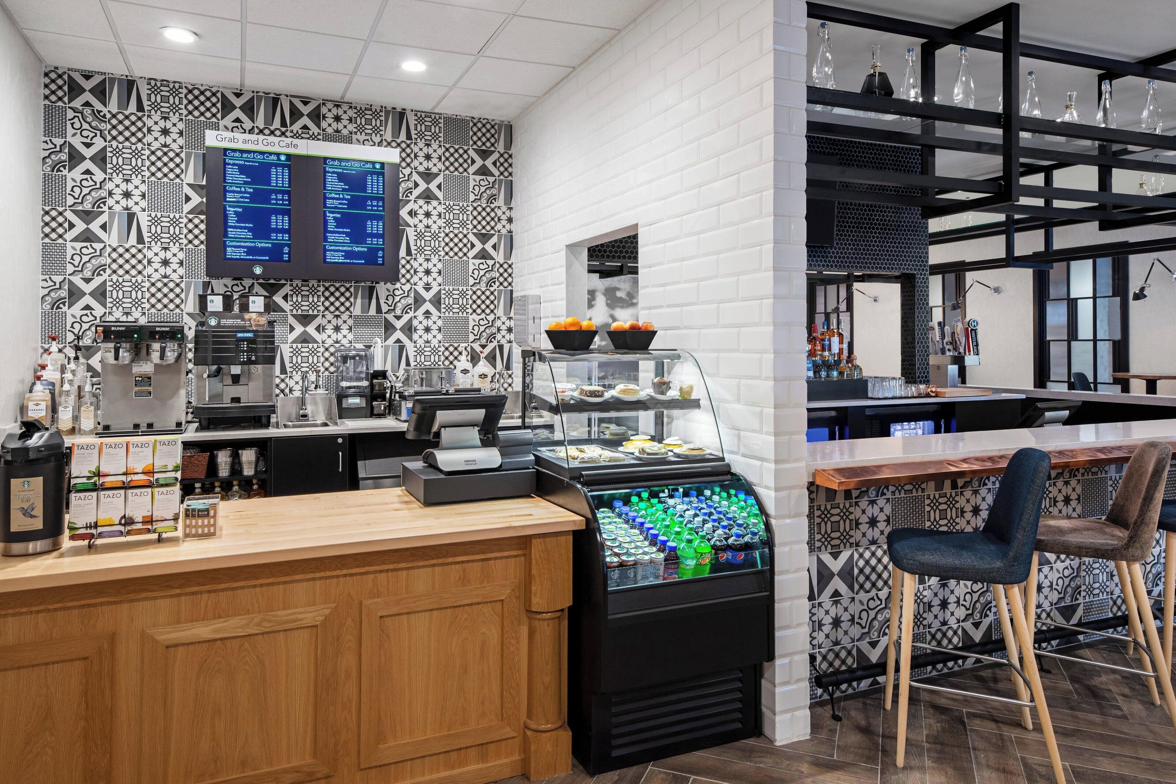 A modern cafe with a coffee machine, a digital menu board, and a beverage dispenser.