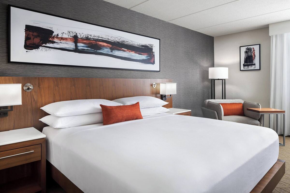A hotel room with a large bed, two bedside tables, a desk, and a chair.