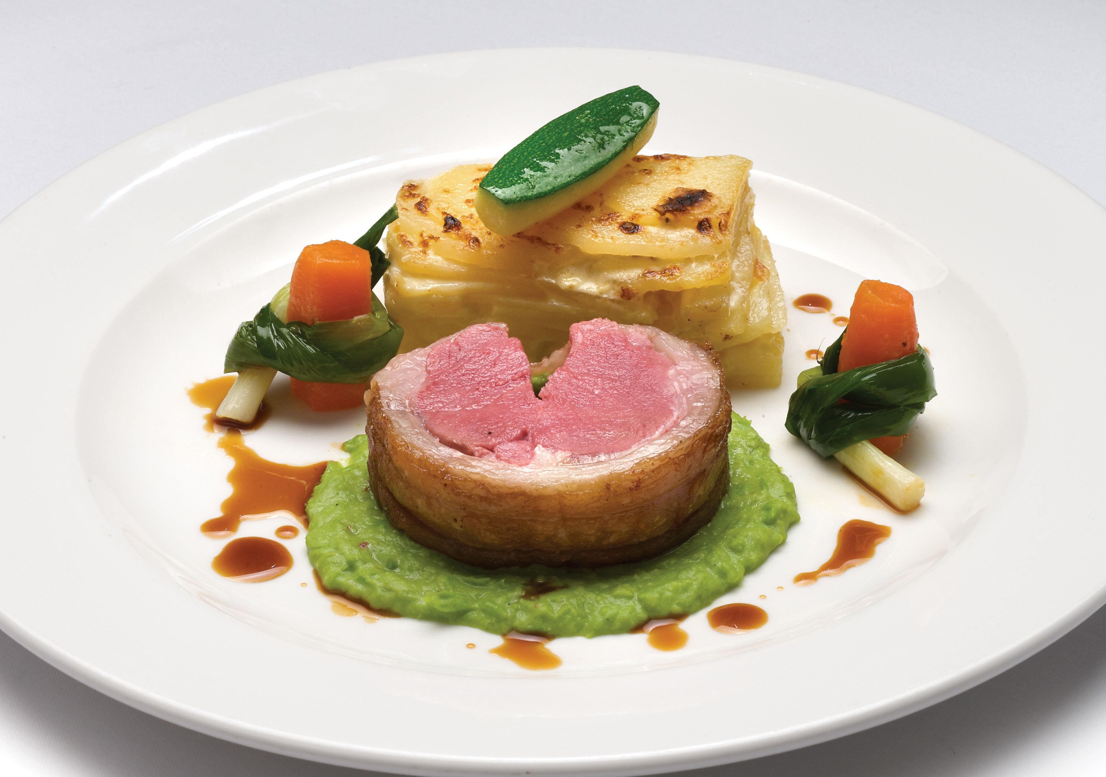 A plate with a slice of meat, a piece of potato, and some vegetables.