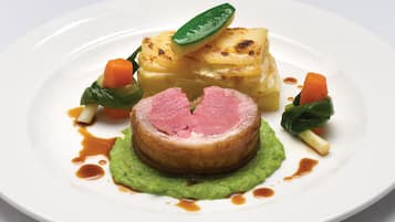 A plate with a slice of meat, a piece of potato, and some vegetables.