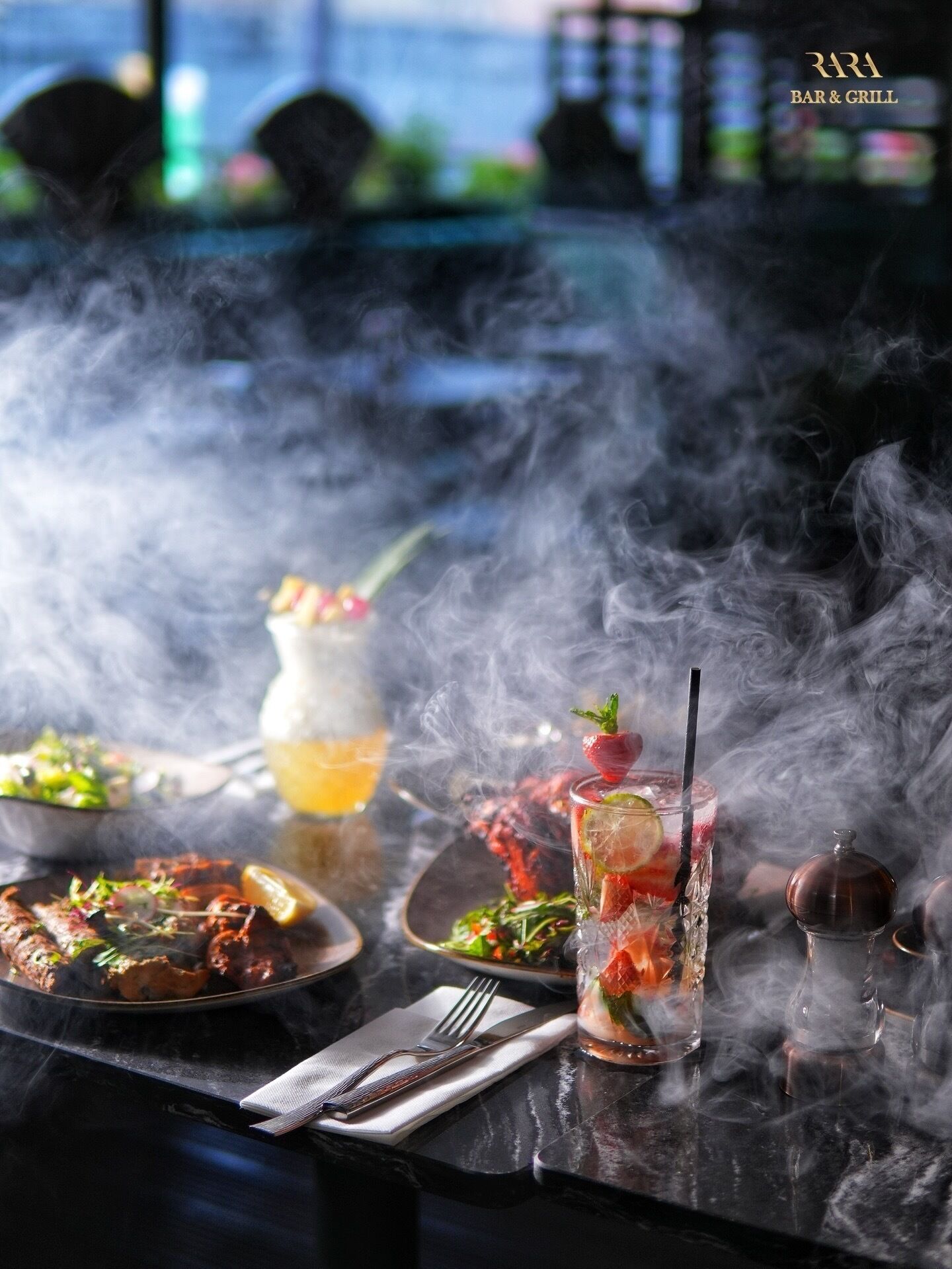 A restaurant setting with a bar, a glass of cocktail with a straw, and a plate of food.