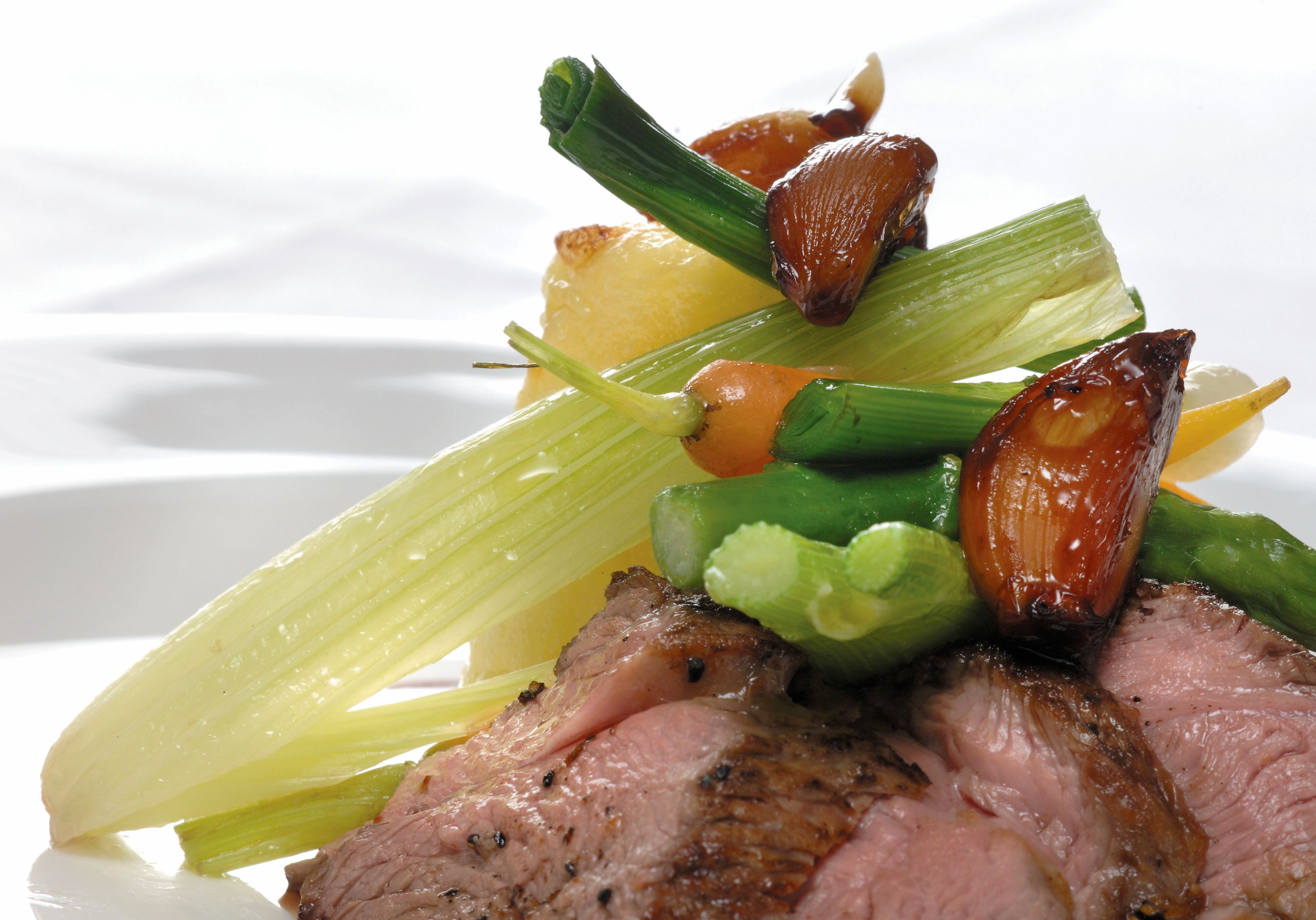 A plate of food with roasted meat, vegetables, and a lemon wedge.