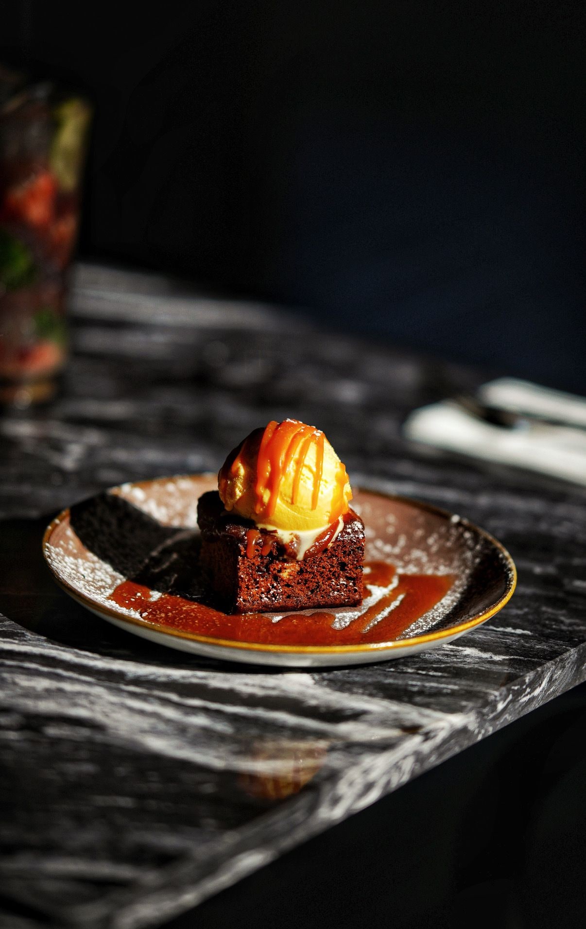 Un postre en un plato sobre un fondo oscuro.
